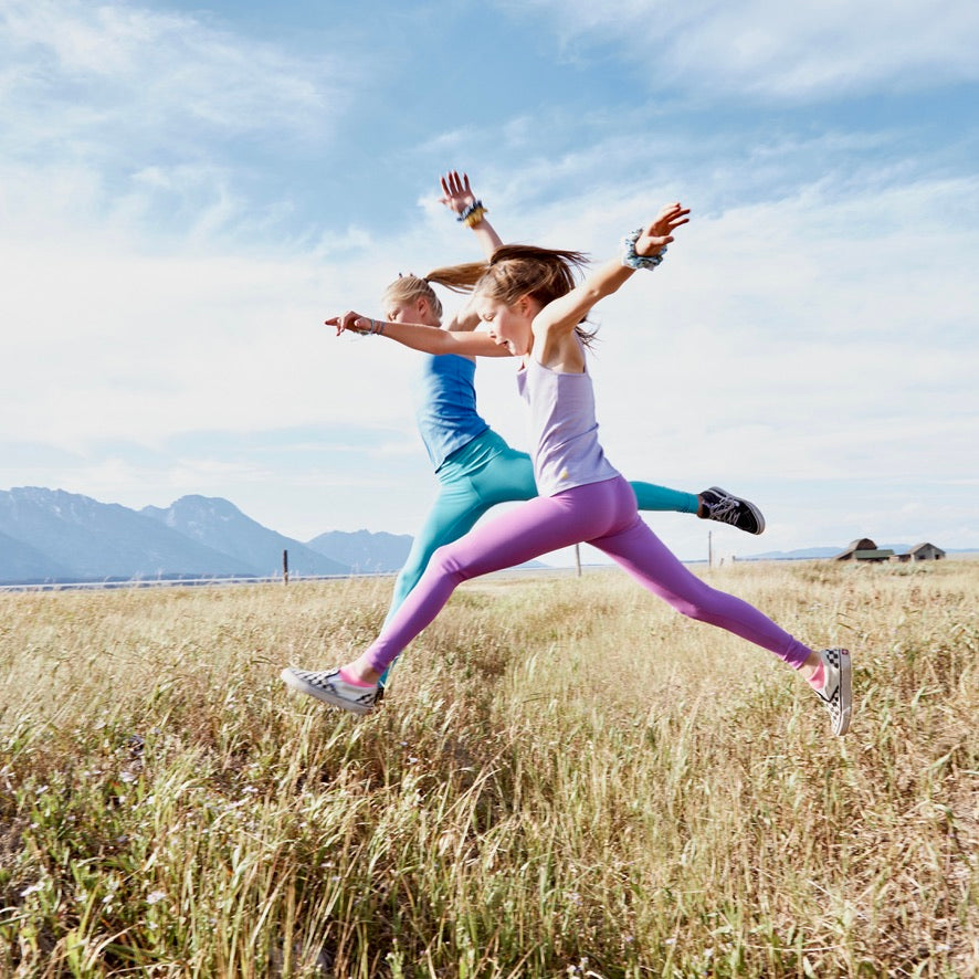 Yellowberry Girls Jane Classic Everyday Cotton Camisole Tank Top. This super soft, single-layer cami features a lovely scoop neck with a delicate finish detail and a fully hemmed bottom. Made with high-quality, luscious fabric that offers a great fit, wonderful coverage and lots of support. It's also a fantastic option for sensitive skin! This beloved piece is delicately perfect. On models jumping across creek.