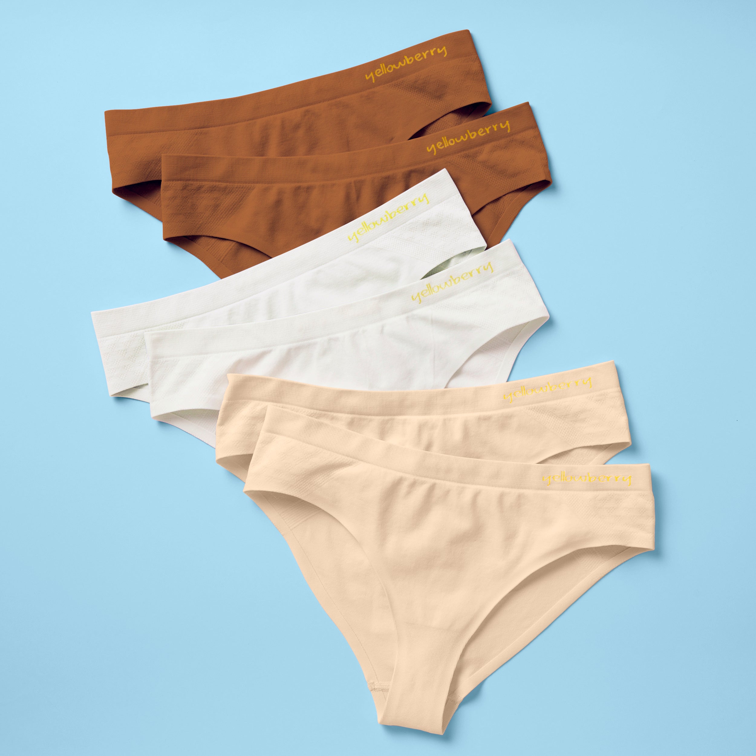 Best-Selling Twistr Girls Seamless Bikini cut underwear by Yellowberry. Front image of sunset (white, beige, mocha colors) bundle on blue background. 