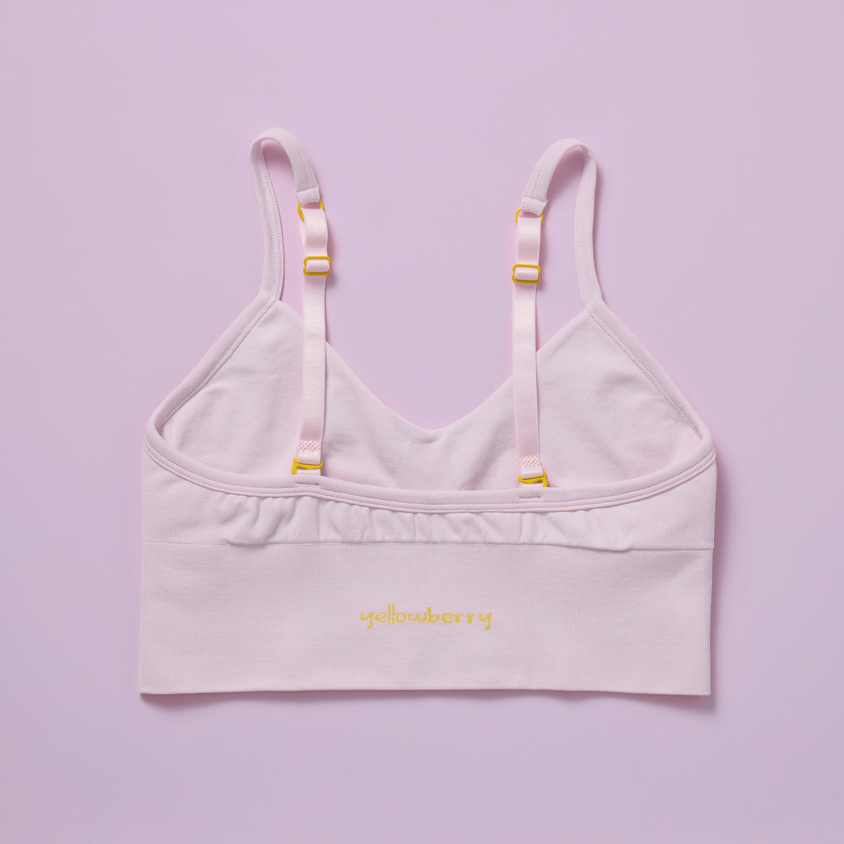 Light pink bralette with thin straps on a light purple background