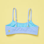 Yellowberry Pipit Training Bra for girls in Ocean (light blue) on a light yellow background, back of the bra. The inside color is our beautiful Wave color, a lovely product detail. And, the Yellow Berry Logo is prominent on the back left - as always!
