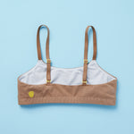 Yellowberry's beautiful pipit cotton training bra in the color mocha photographed as a laydown image of the back of the bra on a light blue background. This best-selling cotton style is super soft, all-natural cotton beginner bra. Supportive everyday bra with no underwires (ever!). High-quality, double-layered fabric. No padding. Designed for girls and daughters with sensitive skin. Machine wash, and dry. 