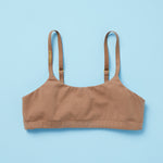 Yellowberry's beautiful pipit cotton training bra in the color mocha photographed as a laydown image of the front of the bra on a light blue background. This best-selling cotton style is super soft, all-natural cotton beginner bra. Supportive everyday bra with no underwires (ever!). High-quality, double-layered fabric. No padding. Designed for girls and daughters with sensitive skin. Machine wash, and dry. 