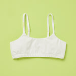 Yellowberry's beautiful pipit cotton training bra photographed as a laydown image of the front of the bra on a light green background. This style is super soft, all-natural cotton beginner bra. Supportive everyday bra with no underwires (ever!). High-quality, double-layered fabric. No padding. Designed for girls and daughters with sensitive skin. Machine wash, and dry. 