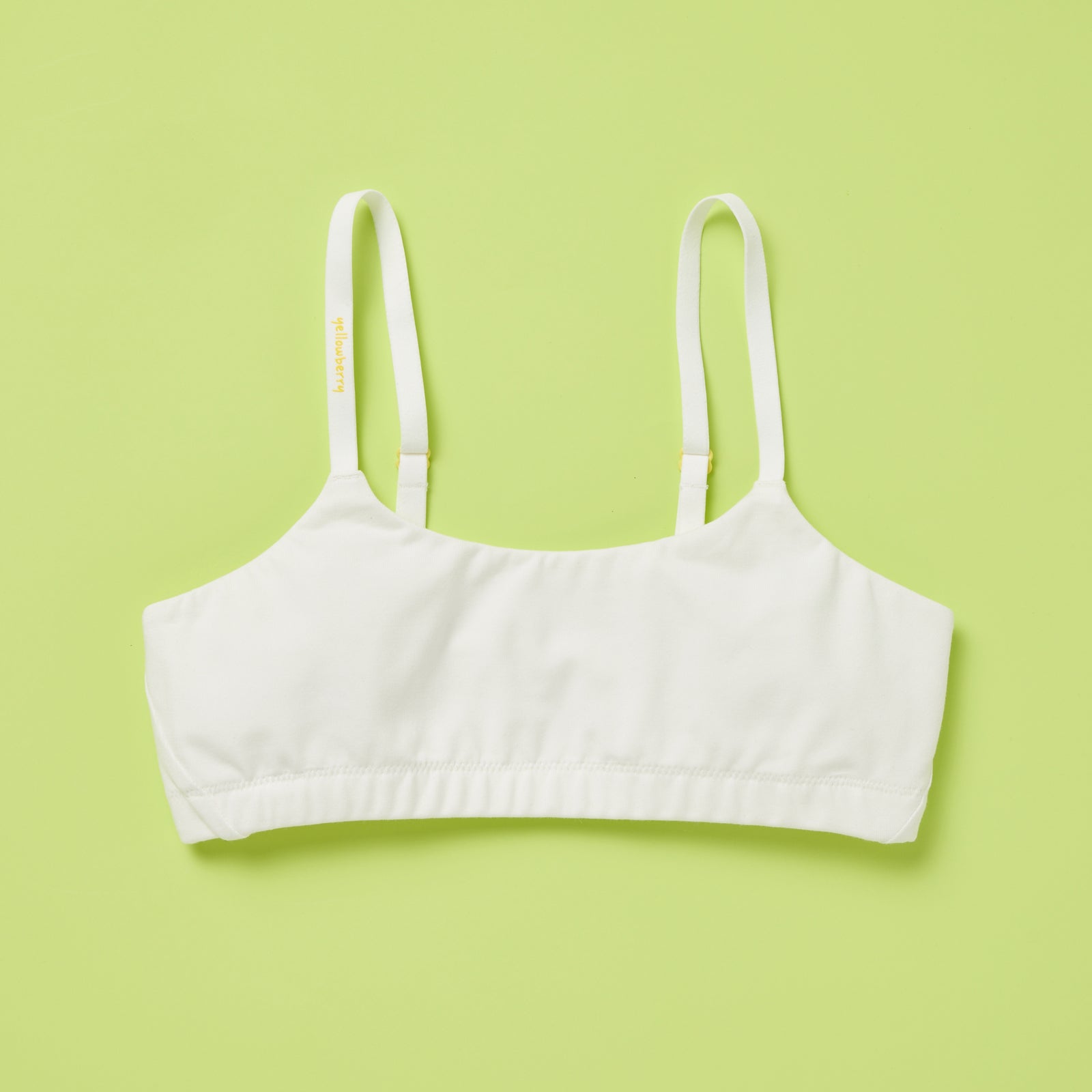 Yellowberry's beautiful pipit cotton training bra photographed as a laydown image of the front of the bra on a light green background. This style is super soft, all-natural cotton beginner bra. Supportive everyday bra with no underwires (ever!). High-quality, double-layered fabric. No padding. Designed for girls and daughters with sensitive skin. Machine wash, and dry. 