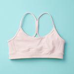 Tink Sports Bra by Yellowberry in a soft brushed nylon blend in a customer favorite color, Bubblegum Pink. Classic pullover design with full support ensures a all-day ease and comfort. Bubblegum is a great new neutral with a sugar twist. Lay down image of Front Tink Bubblegum against a turquoise background.