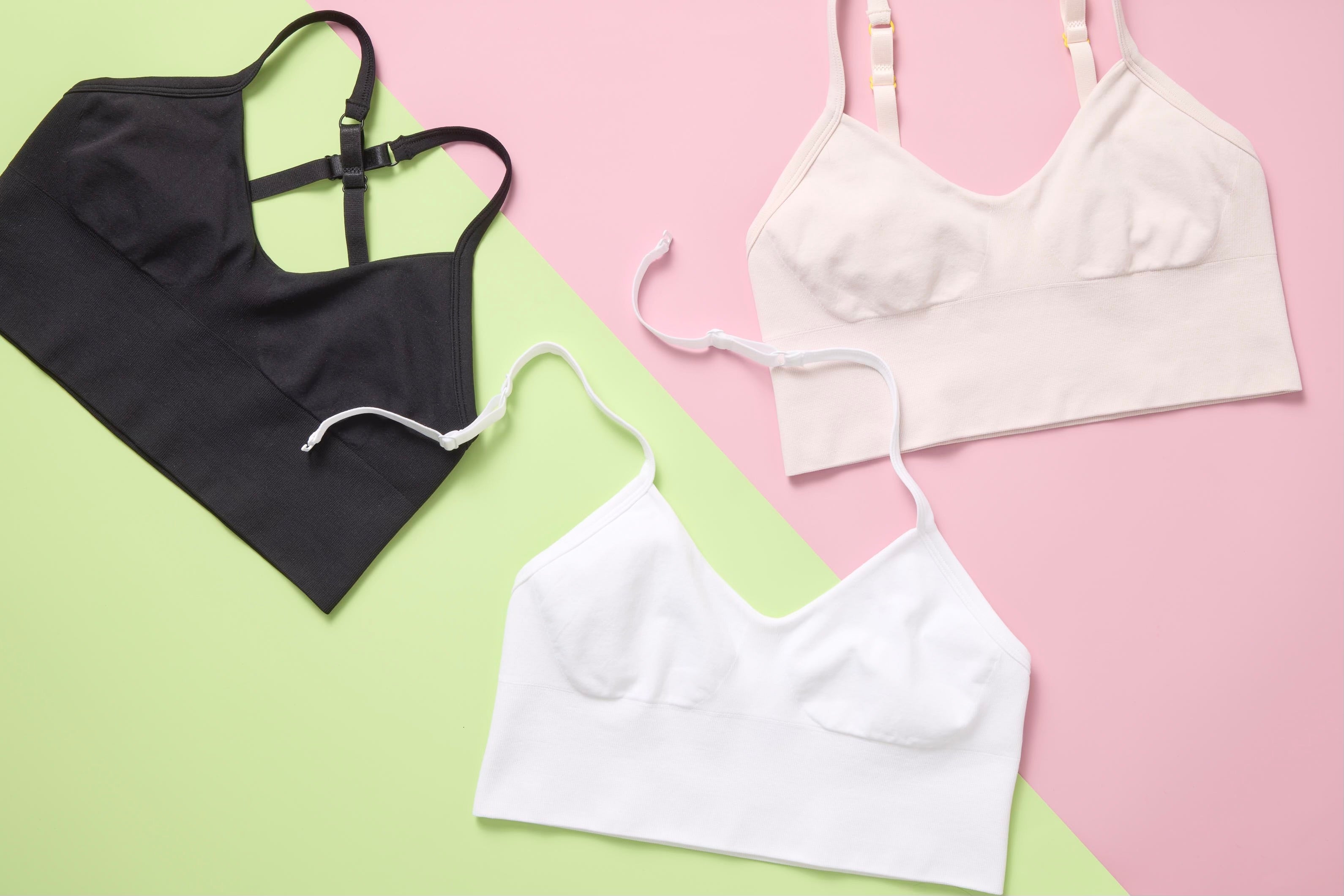 Three bras in black, white, and pink on a green and pink background