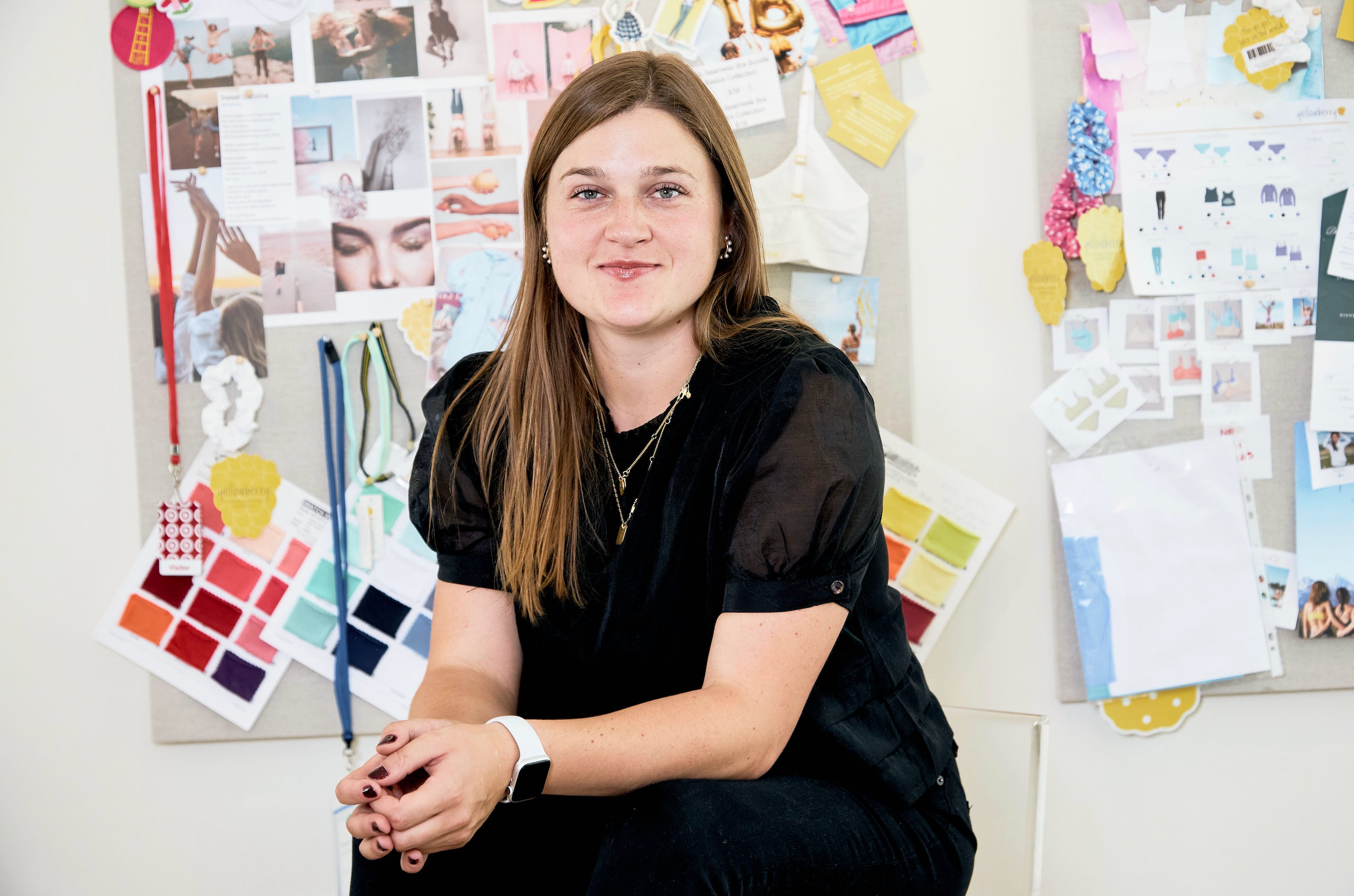 Woman sitting in front of a wall with design materials and color swatches.
