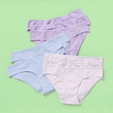 Eight pairs of women's high-waisted briefs in pastel shades of lavender, light blue, and off-white, arranged in a stacked fan layout on a solid light green background.