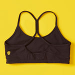 Black sports bra with a yellow logo on a yellow background