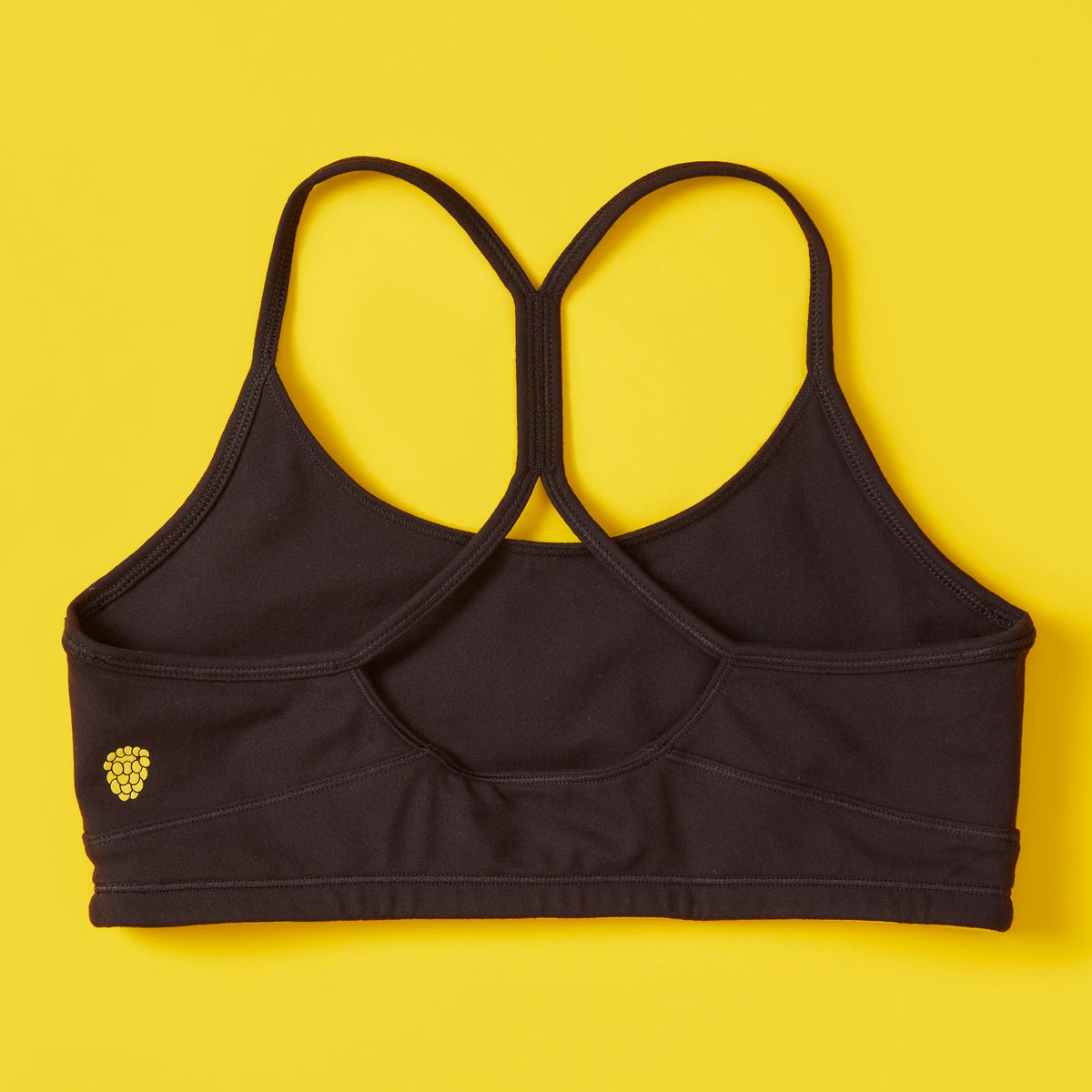 Black sports bra with a yellow logo on a yellow background