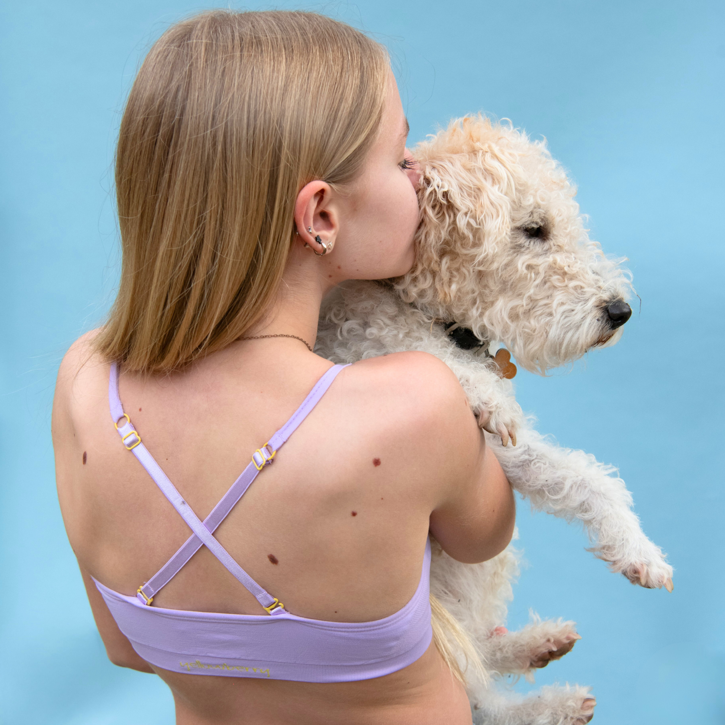 Woman holding a small white dog against a blue background