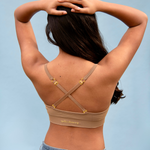 Woman wearing a bralette with gold accents against a light blue background