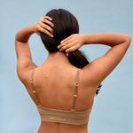 Woman wearing a seamless bralette with gold clasps against a light blue background