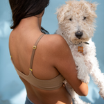 Woman holding a white dog against a blue sky background