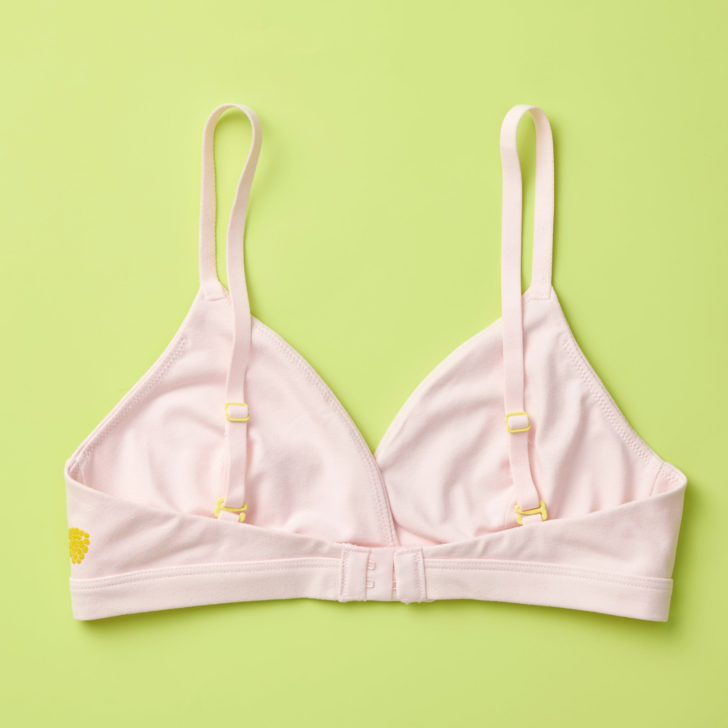 Yellowberry Butter Bra in bubblegum light pink, back laydown detail image. The BEST Bra We Make for More Developed Girls. Fabric is smooth to the touch and made with a matte brushed finish for extra softness. Made with synthetic fabric blend and hook and eye clasp closure. Great for developing girls. Wear and wash is over and over again, it will still look brand new. It will grow with your daughter as she continues to grow, great option for any occasion.