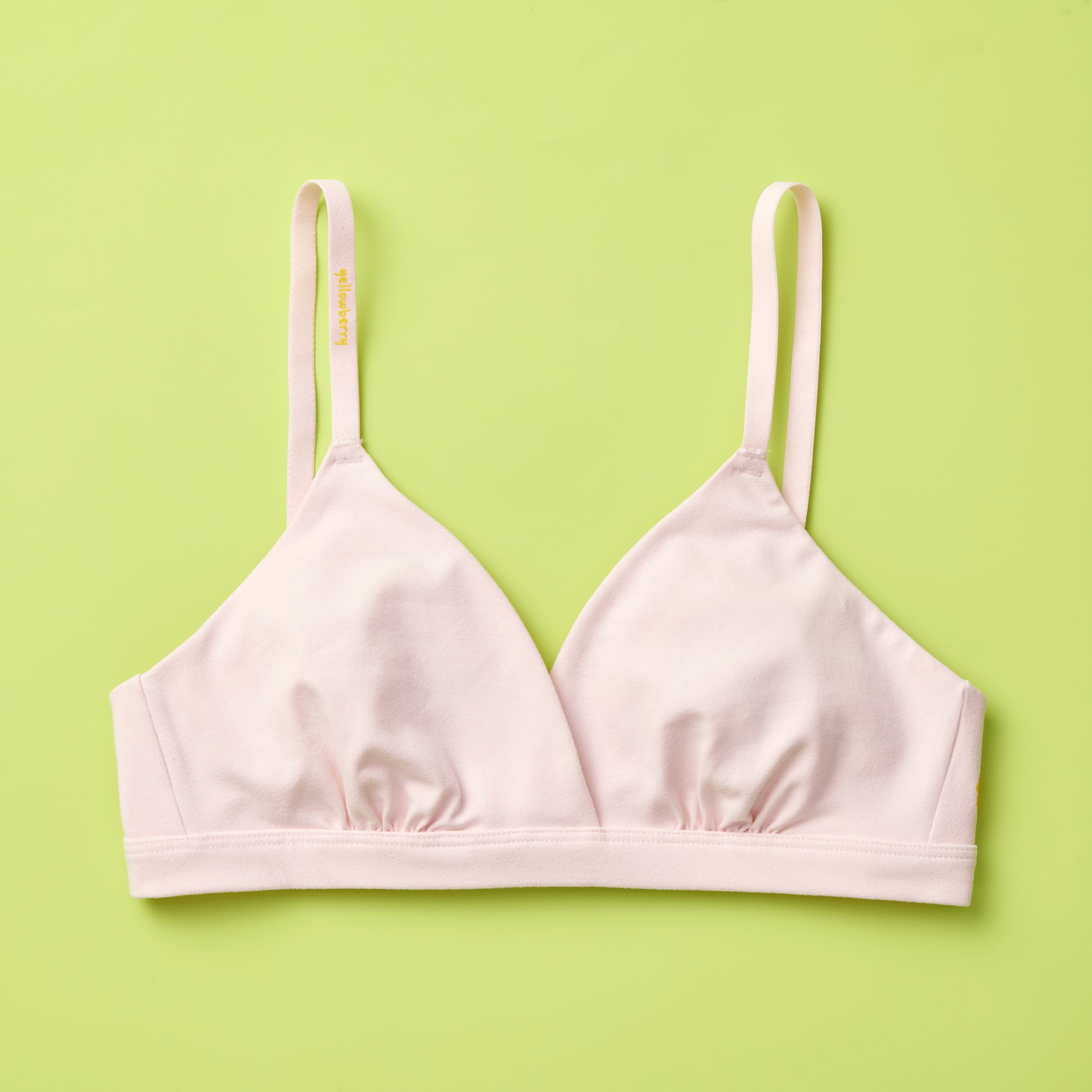 Yellowberry Butter Bra in bubblegum (light pink), front laydown detail image. The BEST Bra We Make for More Developed Girls. Fabric is smooth to the touch and made with a matte brushed finish for extra softness. Made with synthetic fabric blend and hook and eye clasp closure. Great for developing girls. Wear and wash is over and over again, it will still look brand new. It will grow with your daughter as she continues to grow, great option for any occasion.