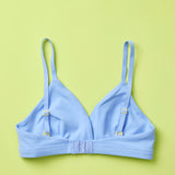 Yellowberry Butter Bra in ocean (a light blue), back laydown detail image. The BEST Bra We Make for More Developed Girls. Fabric is smooth to the touch and made with a matte brushed finish for extra softness. Made with synthetic fabric blend and hook and eye clasp closure. Great for developing girls. Wear and wash is over and over again, it will still look brand new. It will grow with your daughter as she continues to grow, great option for any occasion.