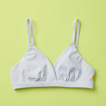 Yellowberry Butter Bra in storm (a light grey), front laydown detail image. The BEST Bra We Make for More Developed Girls. Fabric is smooth to the touch and made with a matte brushed finish for extra softness. Made with synthetic fabric blend and hook and eye clasp closure. Great for developing girls. Wear and wash is over and over again, it will still look brand new. It will grow with your daughter as she continues to grow, great option for any occasion.
