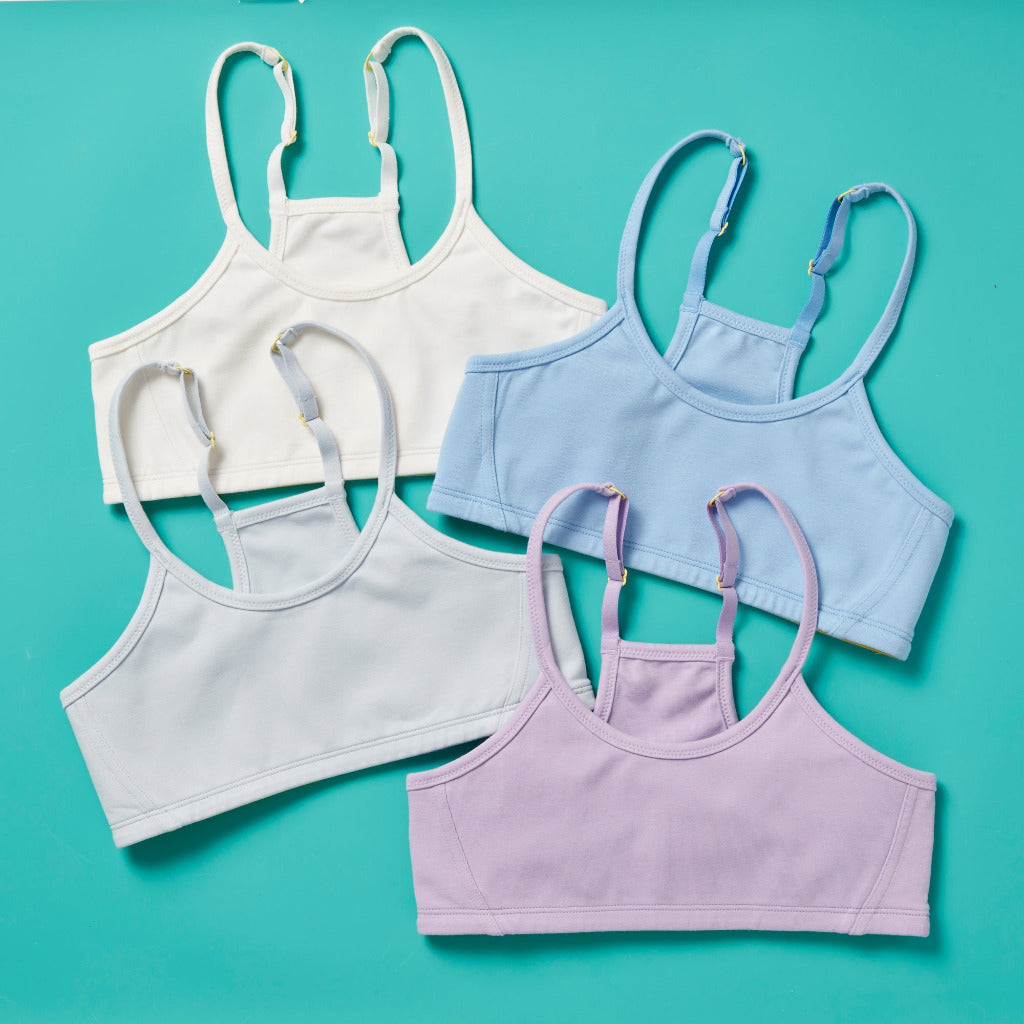 Group image of four Yellowberry Aspen Bras in Puff, Lupin, Iceberg and Droplet (soft light blue, purple, white, blue). Double layered cotton first bra. Everyday bra. Great for middle school and high school. The extra soft cotton is great for sensitive skin. Full coverage, full support. Machine Washable. Cotton fabric. Adjustable straps. Beautiful scoop neckline. Feminine, flattering, supportive. One of our original, long time best-selling bras!