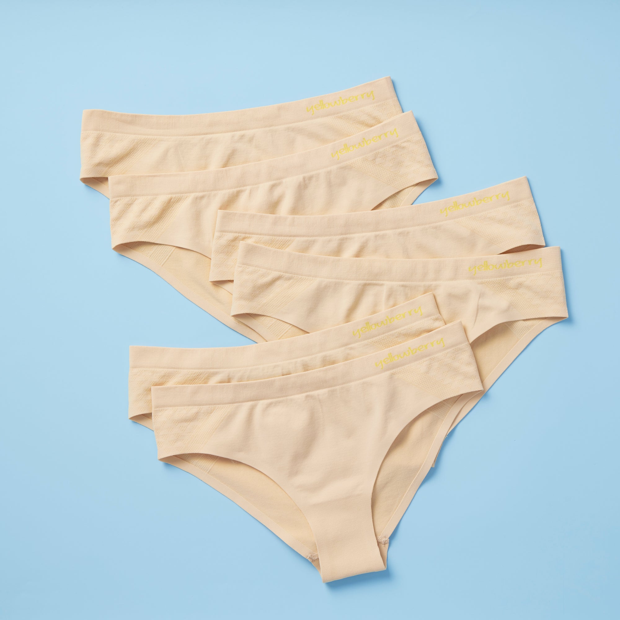 Best-Selling Twistr Girls Seamless Bikini cut underwear by Yellowberry. Front image of doe (beige) bundle on blue background. 