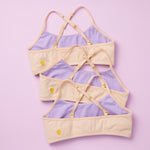 Beautiful Pima Cotton Ladybug Bras in the Doe 3PK Bundle. Three beige bras with lavender lining and crisscross straps, all made from Pima Cotton and photographed on pink background.