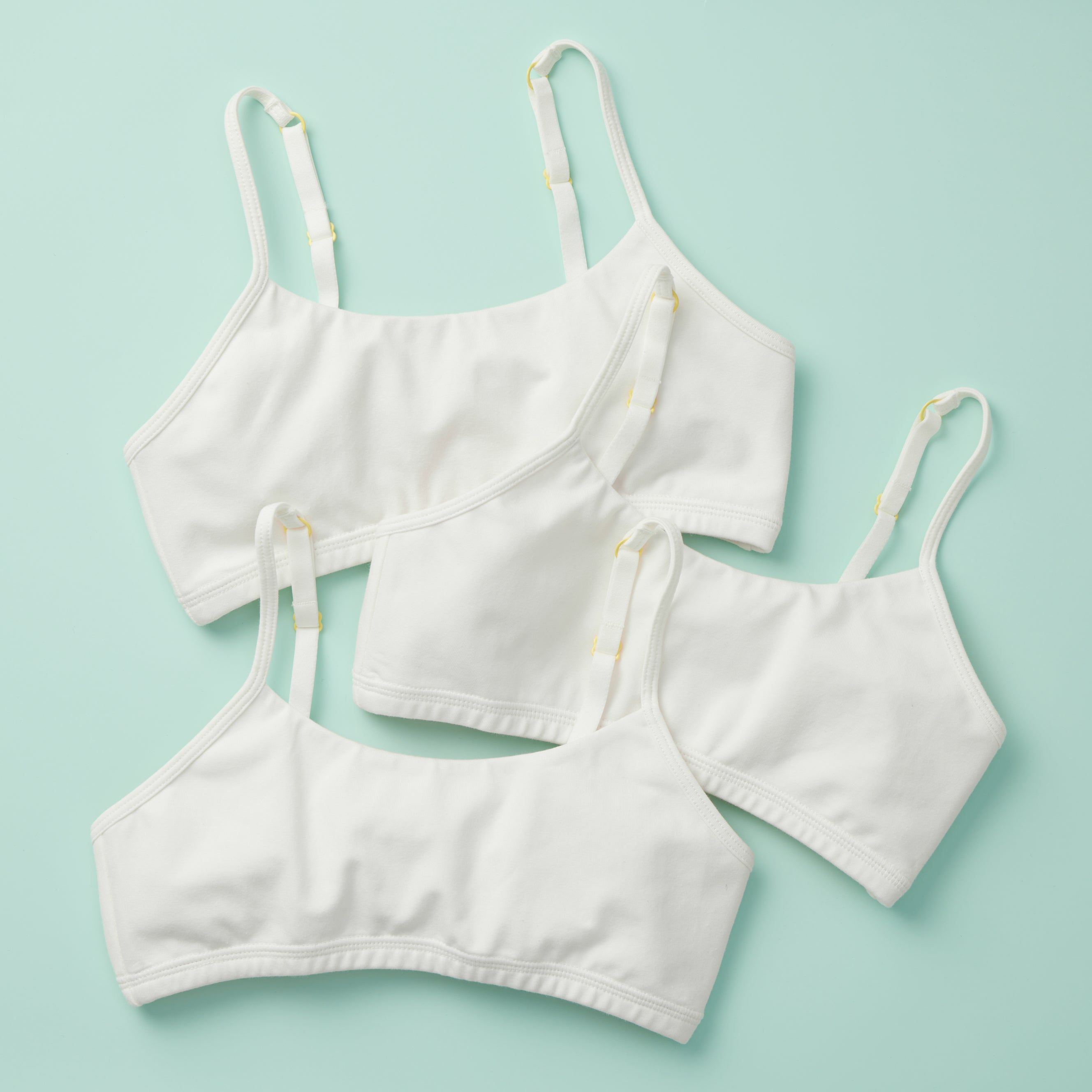 3PK of the original Yellowberry Training Bra for girls. Front Laydown image of three white bras on mint ground. The first bra that changed the industry of bras and underwear.