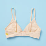 The Yellowberry Lily bra has plenty of room for growth, stretch, and change. Its chic design gives a little more definition and classic support than some of our other bras, with adjustable straps for the best fit. Lilly Bra back Doe Beige on light blue background.
