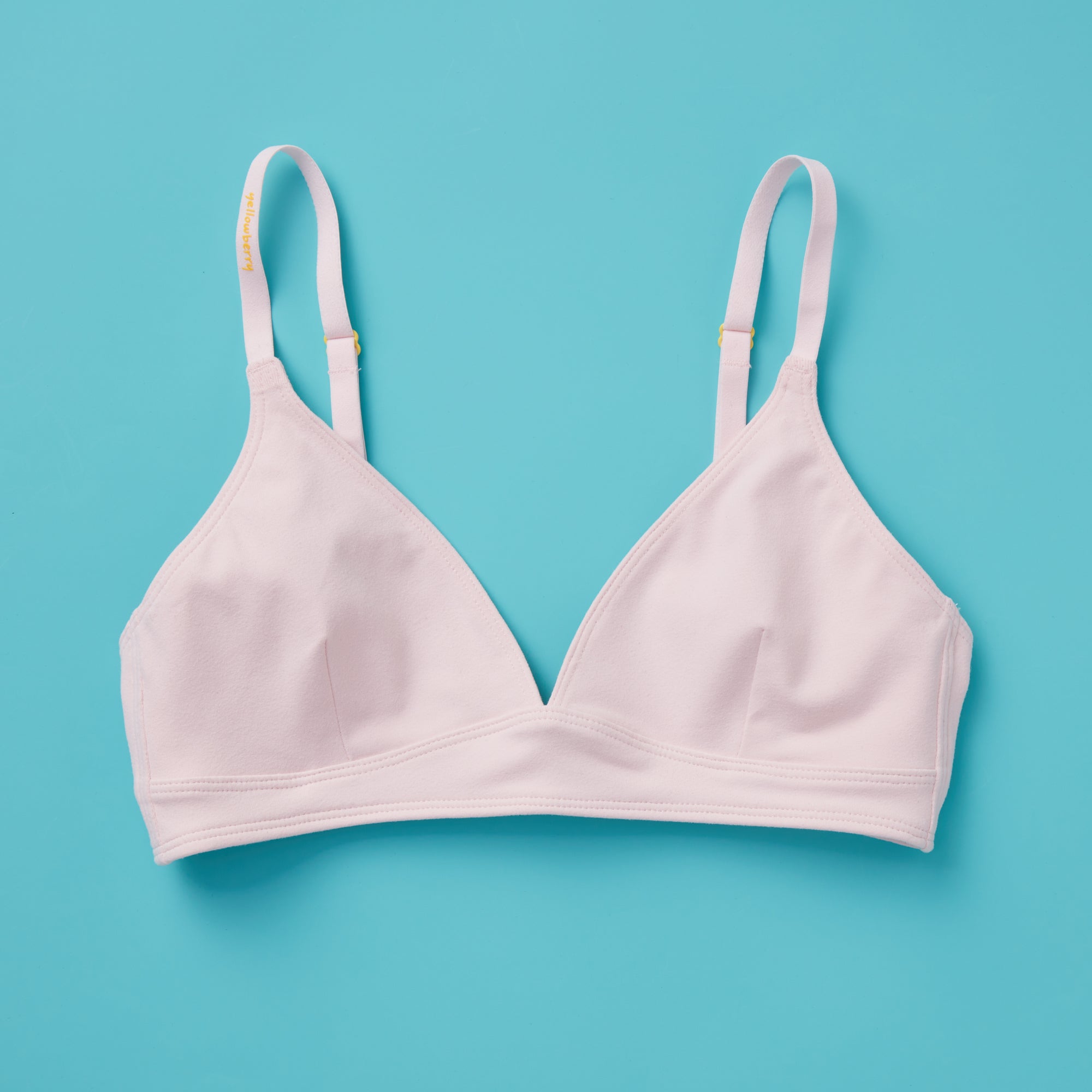 Yellowberry ever popular Lily bra in customer favorite Bubblegum pale pink has plenty of room for growth, stretch, and change. Its clean, simple design gives a little more definition and classic support than some of our other bras, with adjustable straps for the best fit. Lilly Bra Bubblegum front image against turquoise background.