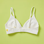 The Yellowberry Lily bra has plenty of room for growth, stretch, and change. Its chic design gives a little more definition and classic support than some of our other bras, and the back hook and eye clasp offers easy adjustments for the best fit. Lilly Bra back Snowflake color lay down image on lime green background.