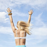 Designed with more developed girls in mind, the Yellowberry Lily bra has plenty of room for growth, stretch, and change. Its chic design gives a little more definition and classic support than some of our other bras, and the back hook and eye clasp offers easy adjustments for the best fit. On model hands in the air white Snowflake Lily Bra against blue sky with scrunchies in the wind.