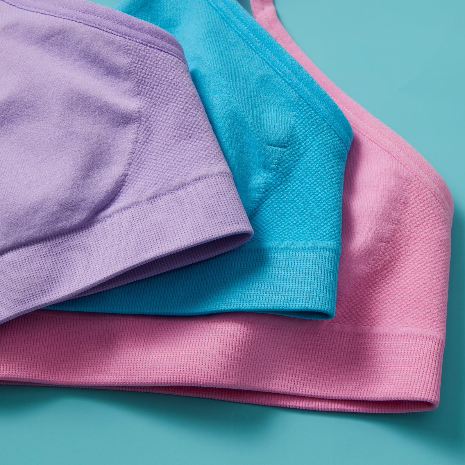 Tulip 3PK Bundle includes one of each color. Lavender, Turquoise, and Pink make a fun, colorful trio of girls' bras. Terrific all day comfort and Yellowberry signature quality. A top drawer favorite. Multi colored Tulip Bundle on a yellow background.