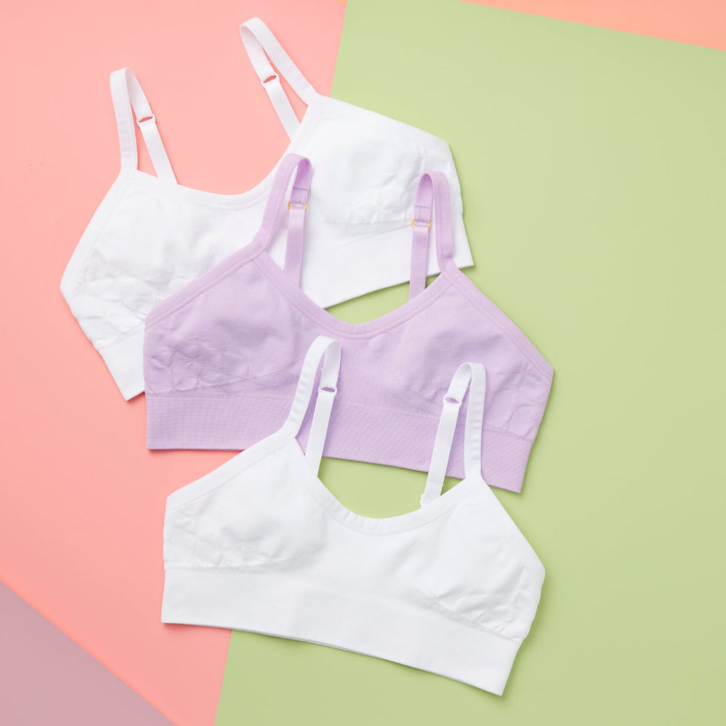 Detail laydown front image of high-quality, all-natural, antimicrobial Yellowberry Seamless Poppy Bra bundle of three. White and light purple colors. Packaged with reusable fabric bags in order to use less plastic, reduce waste, more eco friendly. Bra is best option for girls with skin sensitivities. 