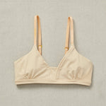 Front close detail image of Yellowberry Wish Bra in beige. The Wish Bra gives supportive definition through shearing and soft space for girls to grow. This means there is room for development without cups, padding, or underwires. The Wish Bra is double-layered and fully lined to ensure full coverage.