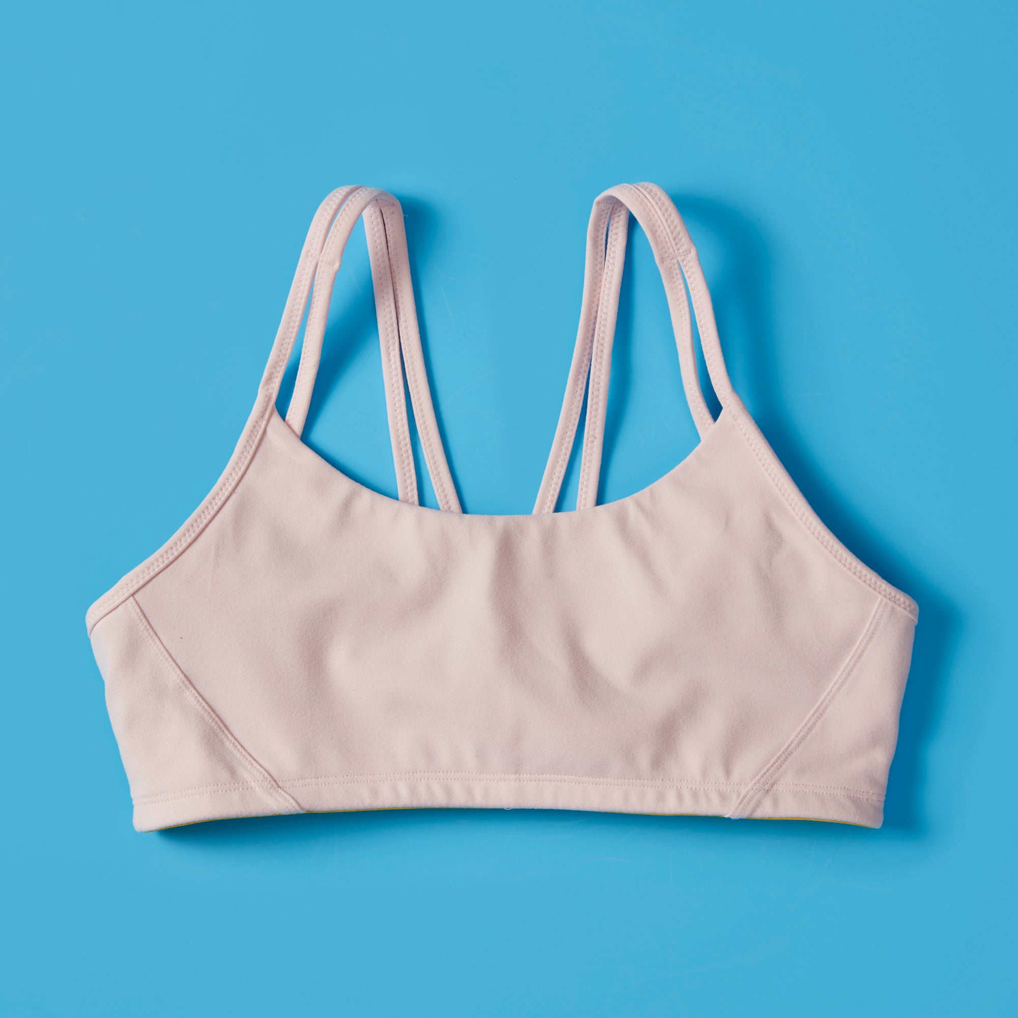 The Luna Bra by Yellowberry in Bubblegum color, front laydown image. The Luna is one of Yellowberry's original hybrid styles; built specifically for girls to move seamlessly from the classroom to practice. It's like two bras in one! Features like smooth fabric and full coverage make the Luna a popular choice for girls looking for bras they can wear all day, every day.