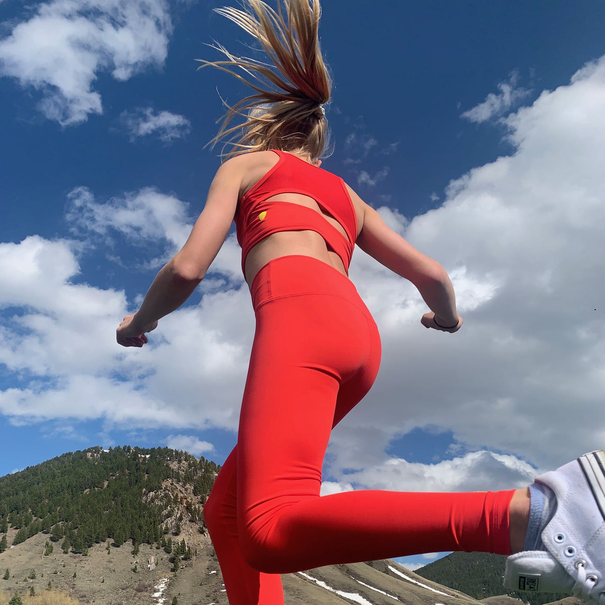 Girl jogging while wearing NEW Hula Crop Bra in Candy Apple (Red) 