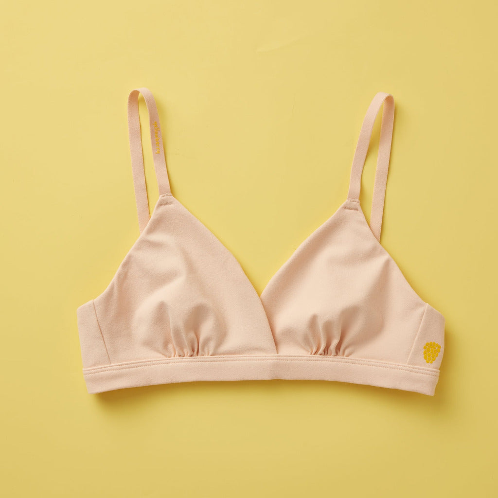 Yellowberry Butter Bra in beige, front laydown detail image. The BEST Bra We Make for More Developed Girls. Fabric is smooth to the touch and made with a matte brushed finish for extra softness. Made with synthetic fabric blend and hook and eye clasp closure. Great for developing girls. Wear and wash is over and over again, it will still look brand new. It will grow with your daughter as she continues to grow, great option for any occasion. Convertible straps. Adjustable straps.