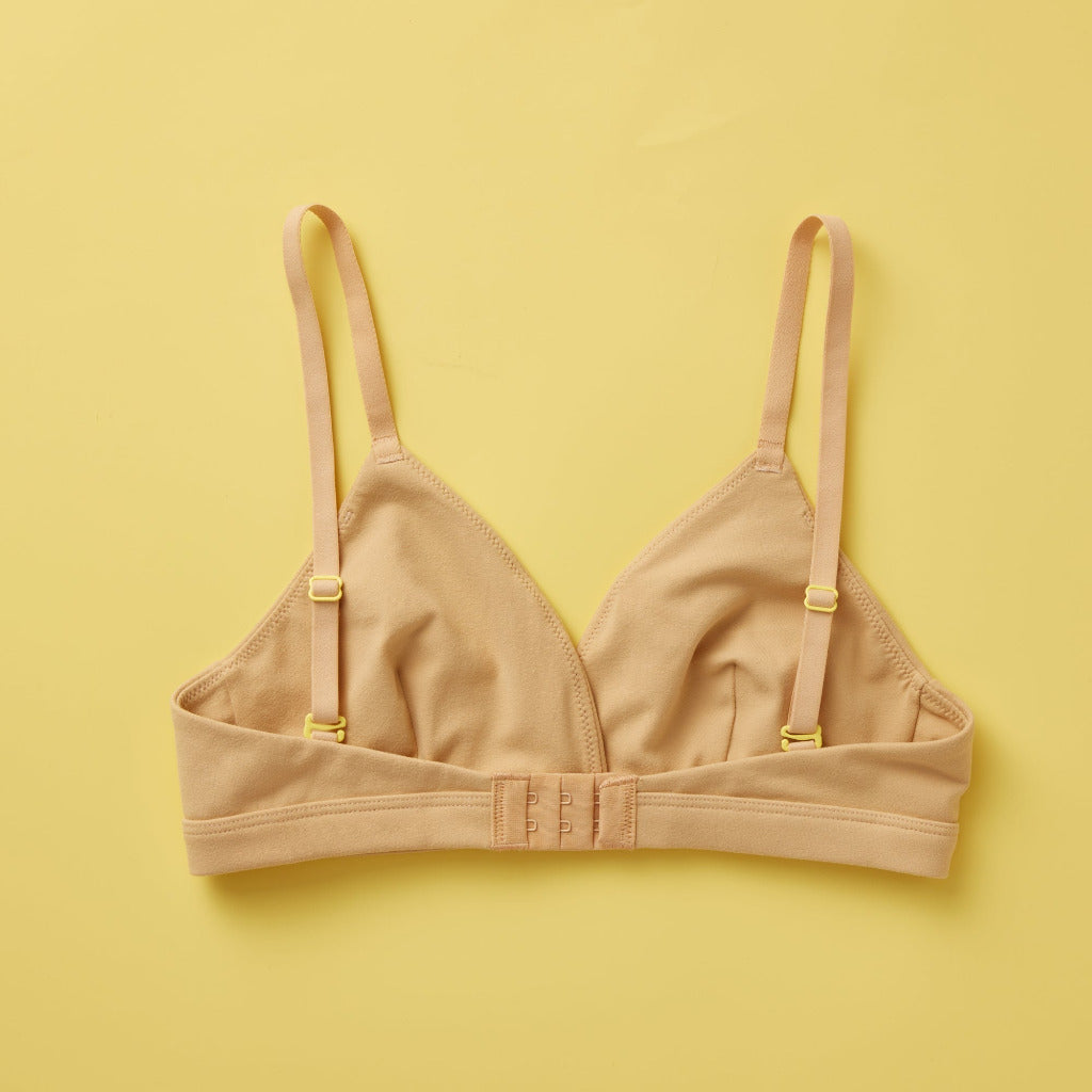 Yellowberry Butter Bra in shade of nude color, back laydown image. The BEST Bra We Make for More Developed Girls. Fabric is smooth to the touch and made with a matte brushed finish for extra softness. Made with synthetic fabric blend and hook and eye clasp closure. Great for developing girls. Wear and wash is over and over again, it will still look brand new. It will grow with your daughter as she continues to grow, great option for any occasion.