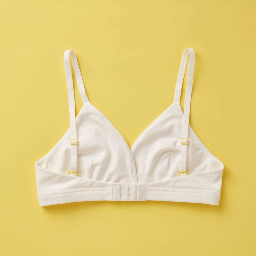 Yellowberry Butter Bra in bright white, back laydown detail image. The BEST Bra We Make for More Developed Girls. Fabric is smooth to the touch and made with a matte brushed finish for extra softness. Made with synthetic fabric blend and hook and eye clasp closure. Great for developing girls. Wear and wash is over and over again, it will still look brand new. It will grow with your daughter as she continues to grow, great option for any occasion.